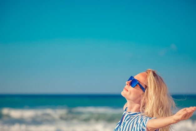 femme heureuse avec les mains ouvertes contre le fond bleu de la mer et du ciel