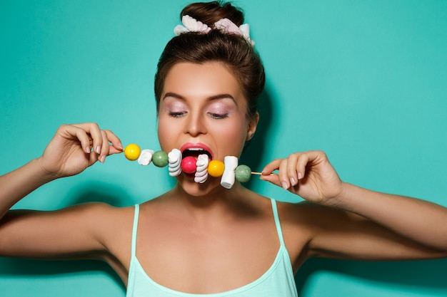 Femme heureuse avec maquillage coloré et bonbons sucrés sur brochette