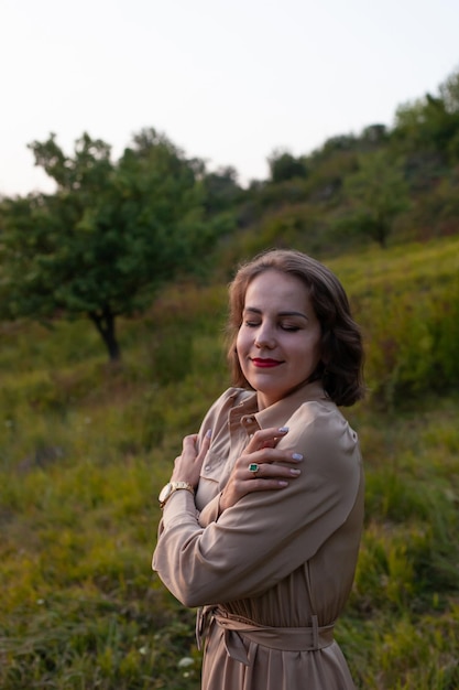 La femme heureuse marche au coucher du soleil sur un parc de colline