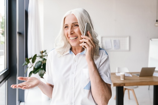 Femme heureuse mature à l'intérieur au bureau