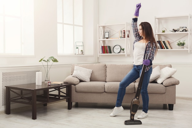 Femme heureuse nettoyant la maison avec l'aspirateur