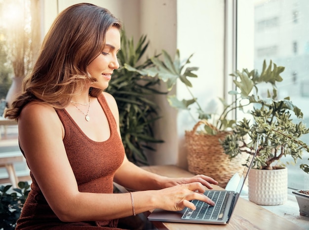 Femme heureuse avec un ordinateur portable ou en tapant dans un café ou un restaurant sur des blogs sur Internet Recherche sur Internet ou cours d'apprentissage Sourire entrepreneur ou travail à distance sur la technologie pour l'écriture indépendante