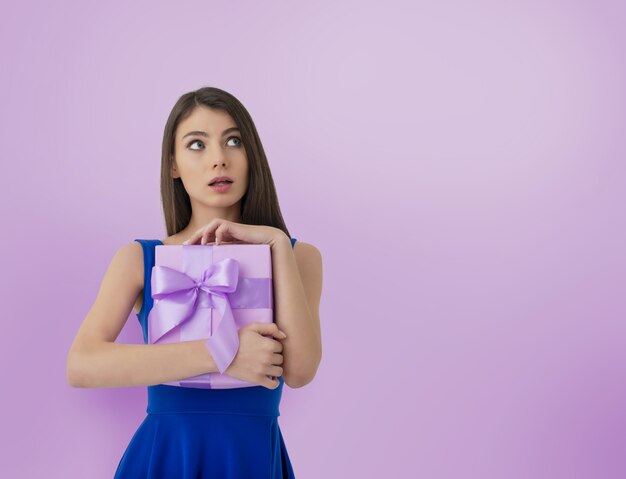 Femme heureuse pense à ce qu'il y a à l'intérieur de son cadeau