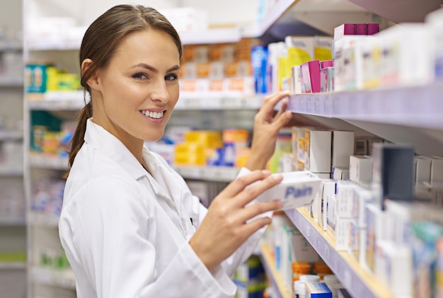 Femme heureuse et pharmacienne sur l'étagère d'une pharmacie fière du service à la clientèle Portrait de personne féminine et sourire ou satisfait de la confiance à la pharmacie pour les médicaments et les ordonnances