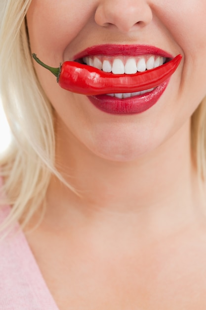 Femme heureuse plaçant un piment rouge dans sa bouche