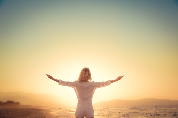 femme heureuse à la plage au coucher du soleil