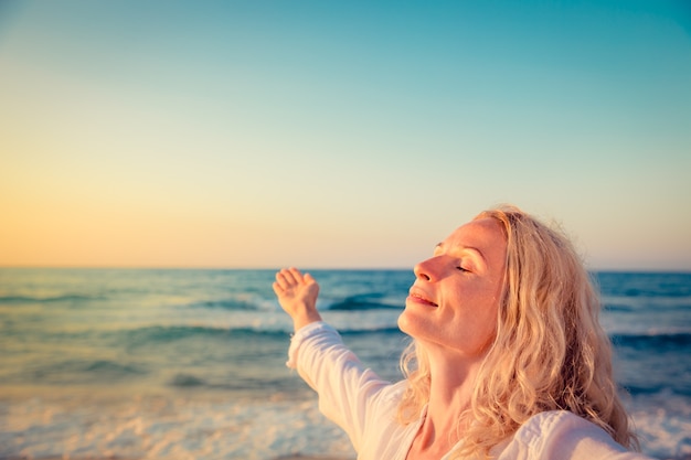 femme heureuse à la plage au coucher du soleil