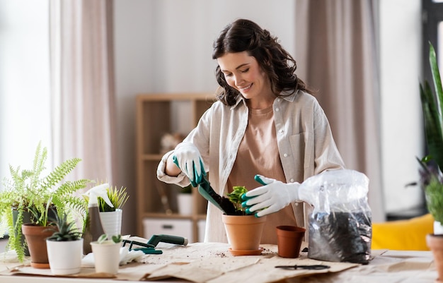 une femme heureuse plantant des fleurs en pot à la maison