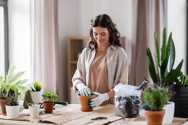 une femme heureuse plantant des fleurs en pot à la maison