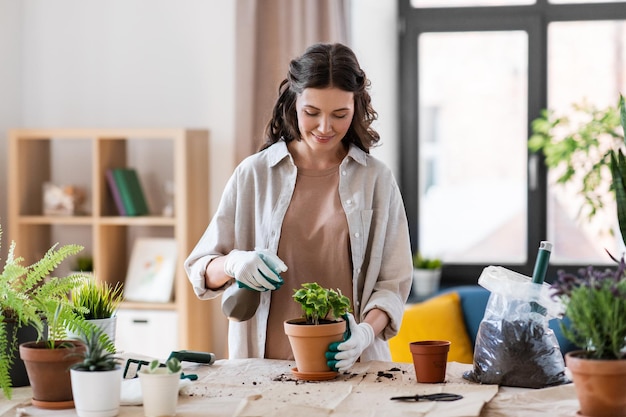 une femme heureuse plantant des fleurs en pot à la maison