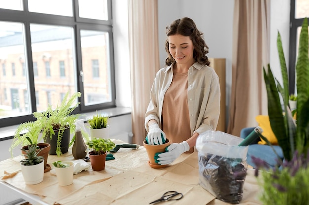 une femme heureuse plantant des fleurs en pot à la maison