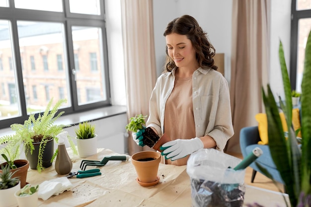 une femme heureuse plantant des fleurs en pot à la maison