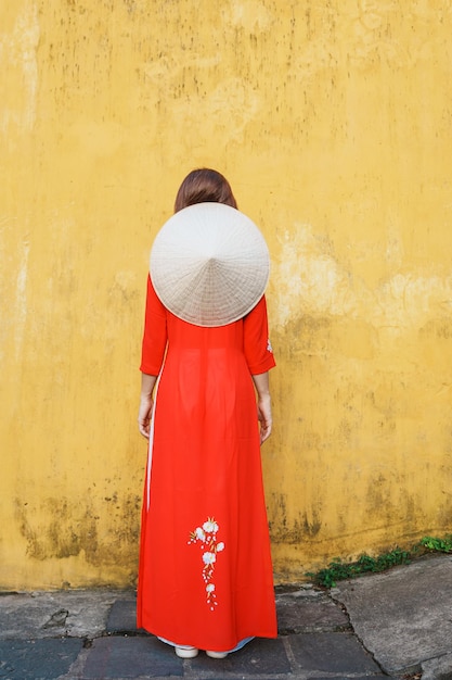 Photo femme heureuse portant une robe vietnamienne ao dai et un chapeau voyageur visitant l'ancienne ville de hoi an dans le centre du vietnam et populaire pour les attractions touristiques concept de voyage au vietnam et dans le sud-est