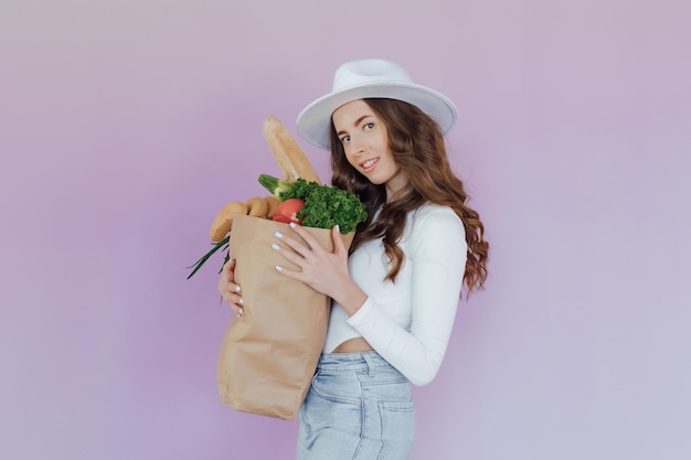 Femme heureuse positive en bonne santé tenant un sac en papier rempli de fruits et de légumes