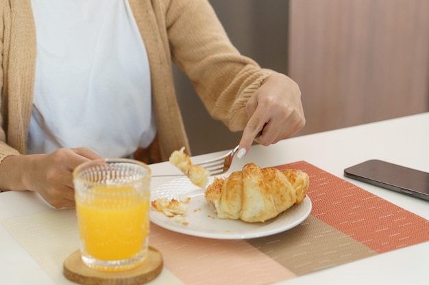 Femme heureuse prenant le petit déjeuner croissants croustillants