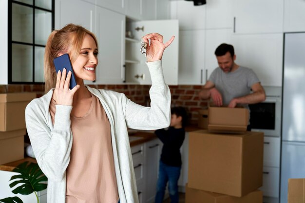 Une femme heureuse qui appelle et tient les clés d'une nouvelle maison.