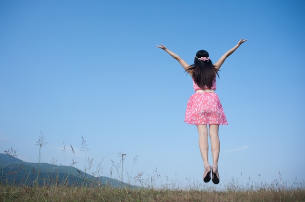 Femme heureuse qui saute avec le ciel bleu