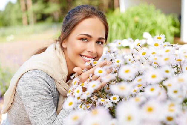 une femme heureuse qui sent les fleurs de camomille dans le jardin