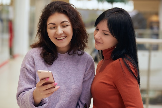 Femme heureuse regardant téléphone intelligent au centre commercial,