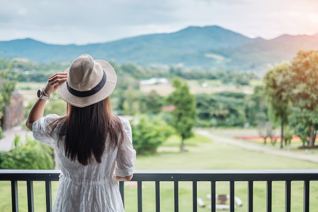 Femme heureuse en robe blanche et chapeau à la belle vue sur la nature.