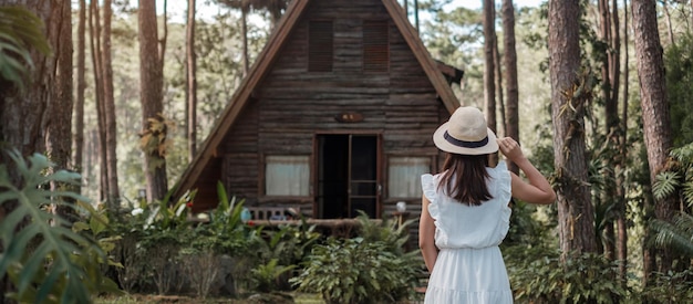 Femme heureuse en robe blanche et chapeau voyageant dans la forêt de pins, visite touristique à Doi Bo Luang, Chiang Mai, Thaïlande, monument et populaire pour les attractions touristiques. Concept de vacances et de voyage