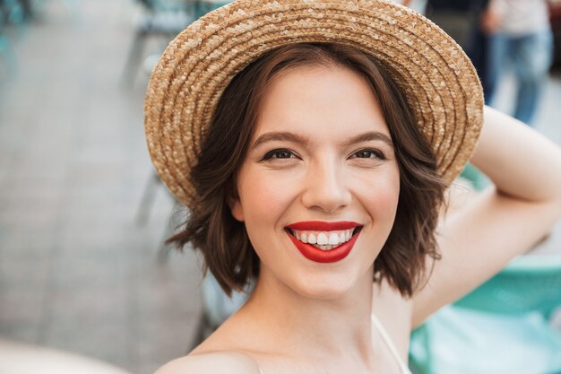 Femme heureuse en robe et chapeau de paille faisant selfie