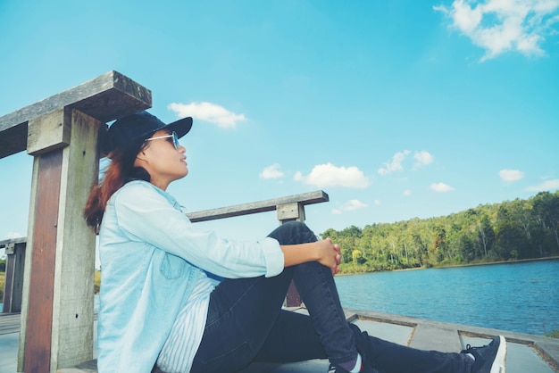 Femme heureuse avec s'asseoir et se détendre et lagon au coucher du soleil