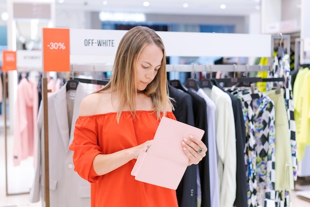 Femme heureuse avec sac à main faisant du shopping en robe rouge