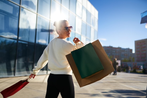Femme heureuse avec des sacs à provisions marchant dans la ville du centre commercial une fille excitée aime les achats sur le noir