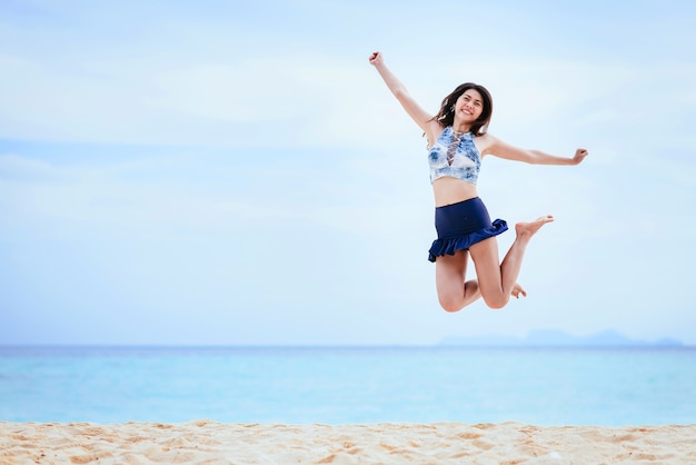 Femme heureuse sautant sur la plage