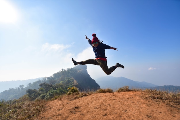 femme heureuse et sauter sur la montagne au sommet de la journée ensoleillée