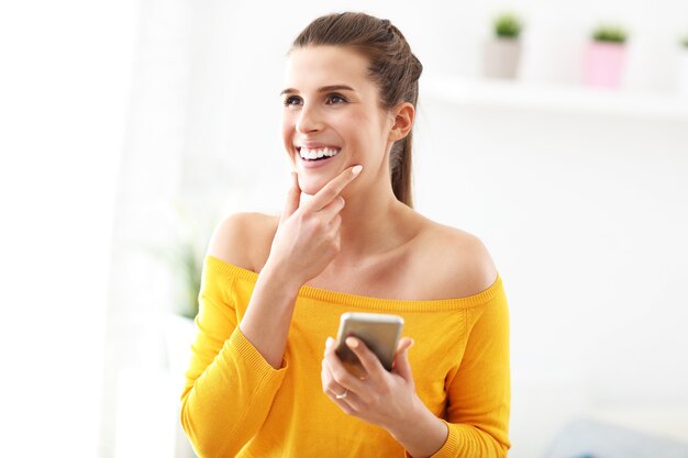 femme heureuse se détendre à la maison avec smarphone