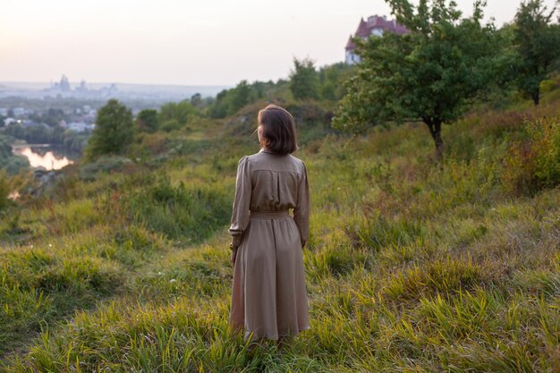 Une femme heureuse se promène au coucher du soleil sur une colline surplombant la rivière