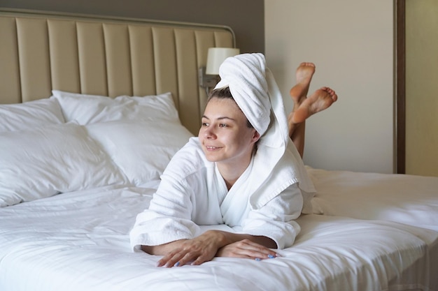 Femme heureuse se reposant allongée sur le lit après une douche à la maison ou dans une chambre d'hôtel