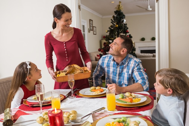 Femme heureuse, servant la dinde rôtie à sa famille