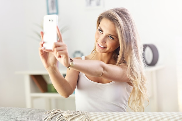 femme heureuse avec smartphone sur canapé