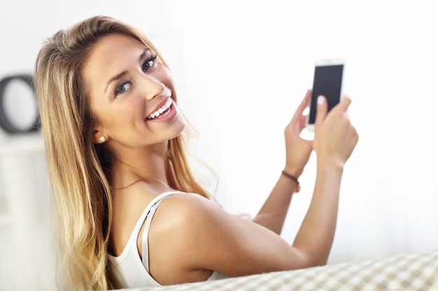 femme heureuse avec smartphone sur canapé