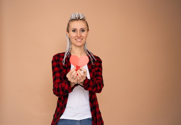 Femme heureuse souriante le jour de la Saint-Valentin avec coeur rouge valentine isolé sur fond beige