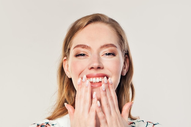 Une femme heureuse et surprise riant sur un fond blanc.