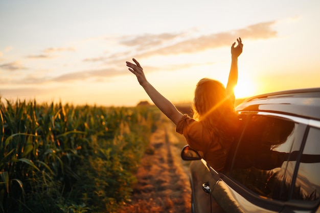 Une femme heureuse tend les bras tout en sortant de la fenêtre de la voiture Mode de vie Voyage tourisme nature