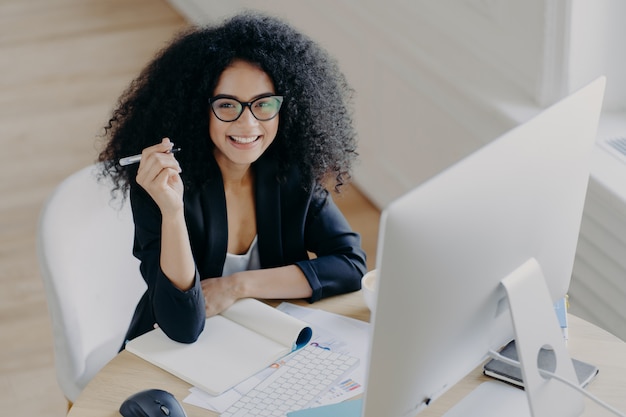 Une femme heureuse tient un stylo et écrit des informations