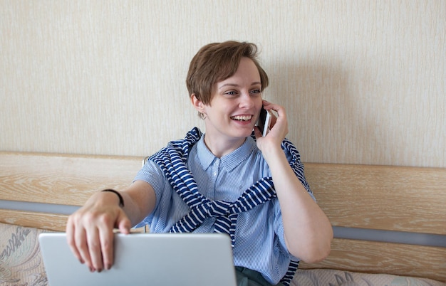 Une femme heureuse travaille avec un téléphone portable à la maison Jeune femme souriante travaillant dans un travail à distance confortable