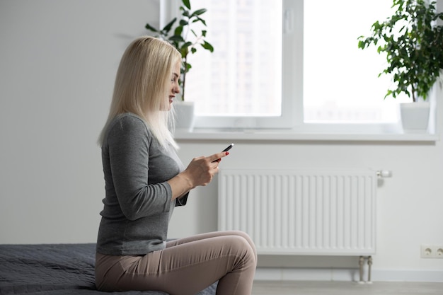 Femme heureuse utilisant un smartphone sur le lit à la maison.