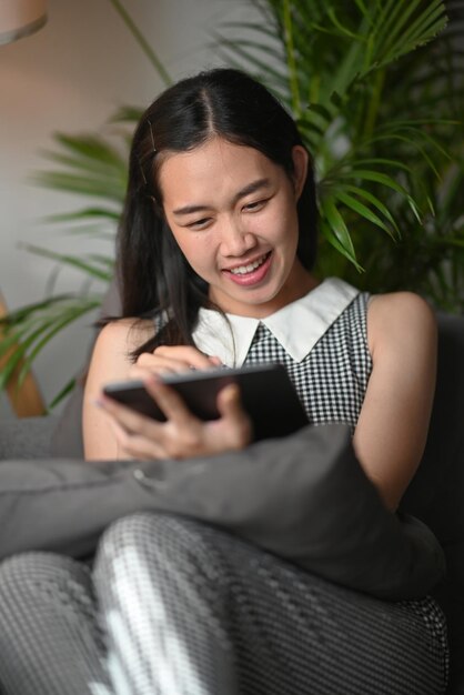 Femme heureuse utilisant une tablette numérique et passant du temps libre à la maison