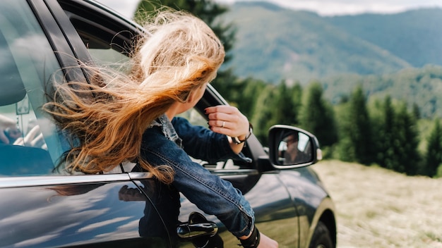 Une femme heureuse voyage en voiture dans les montagnes. Concept de vacances d'été