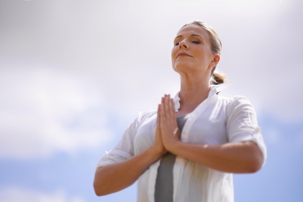 Femme heureuse yoga et méditation dans le bien-être spirituel ou la foi avec un fond de ciel nuageux Personne féminine ou yogi méditant ou les mains ensemble pour prier l'espoir ou la conscience avec de l'air frais dans la nature