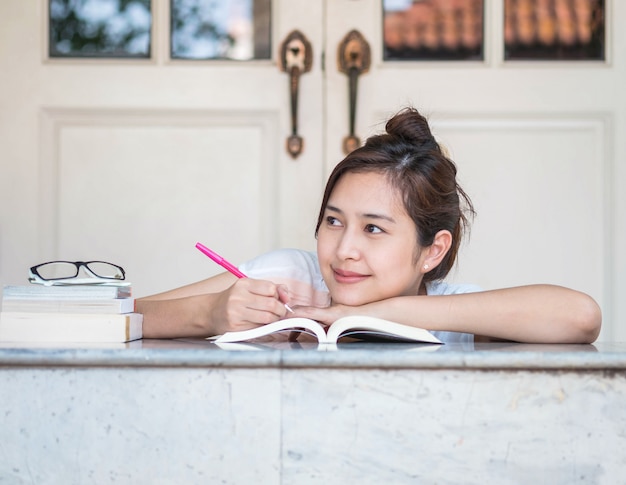 Femme, heureux, visage, livre, marbre, table, devant, maison