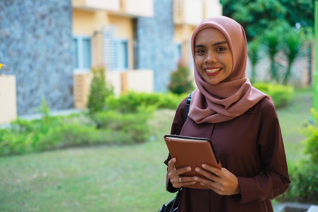 une femme en hijab avec un cahier dans sa main