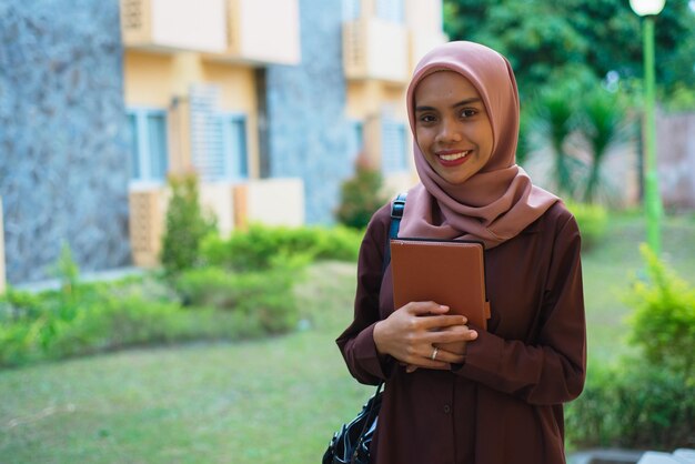 une femme en hijab avec un cahier dans sa main