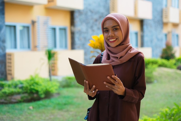 une femme en hijab avec un dossier à la main.